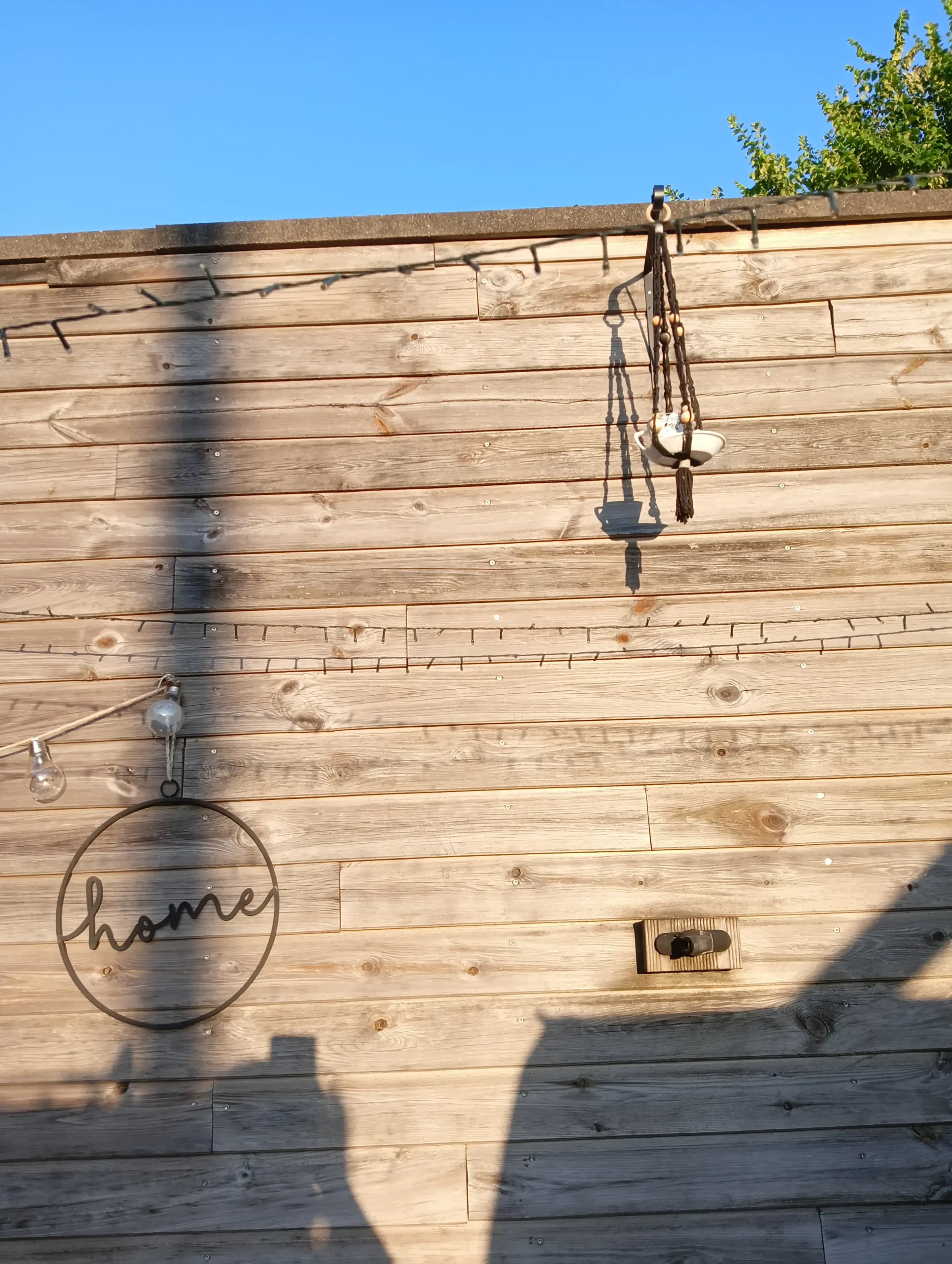 Mangeoire noire fait main accrochée sur un mur de terasse