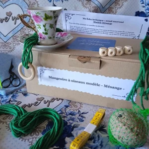 Le kit DIY pour créer une mangeoire à oiseau modèle Mésange exposé avec la tasse, le fils, les perles, la notice