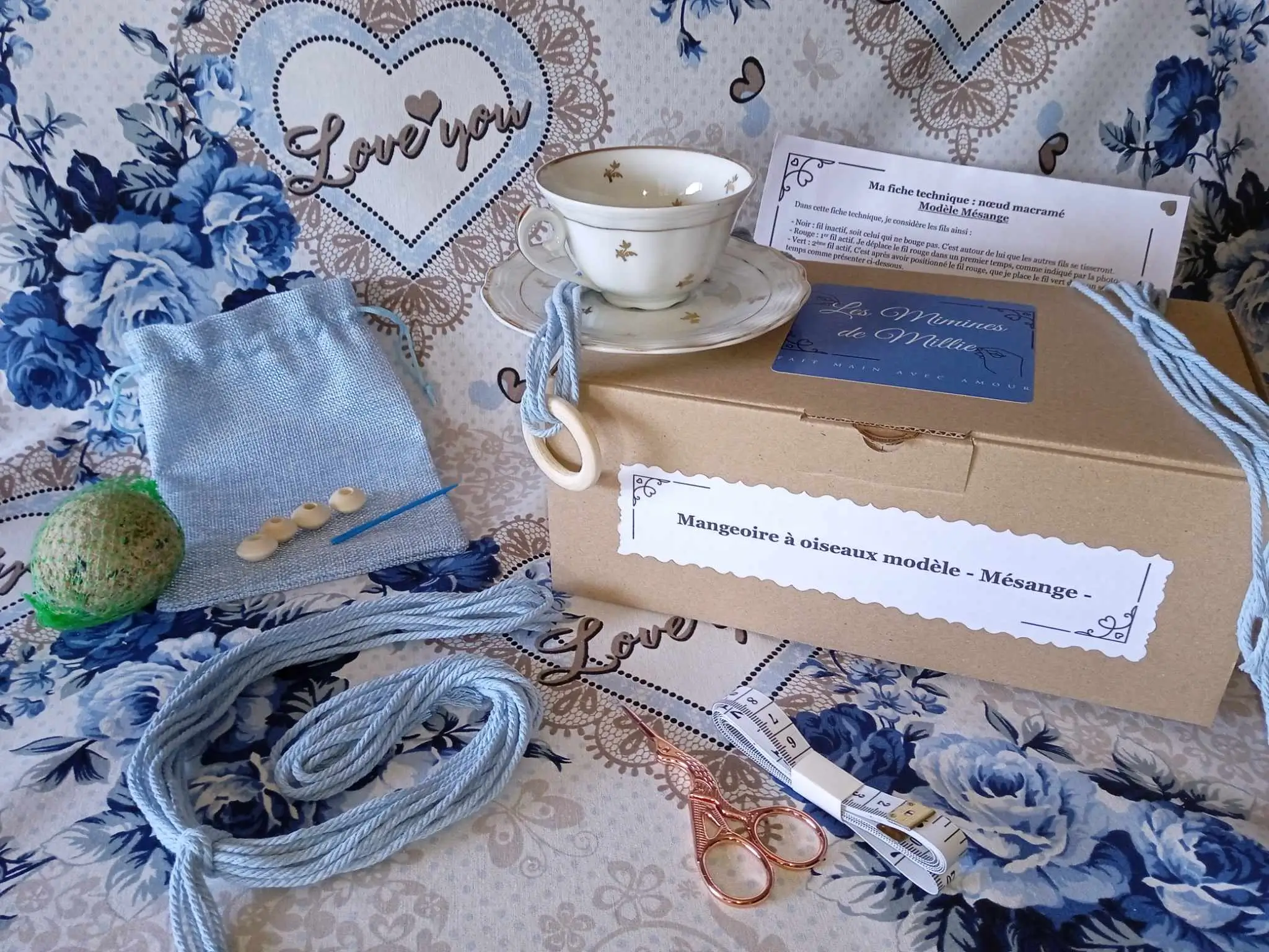 Le kit DIY pour créer une mangeoire à oiseau modèle Mésange exposé avec la tasse, le fils, les perles, la notice