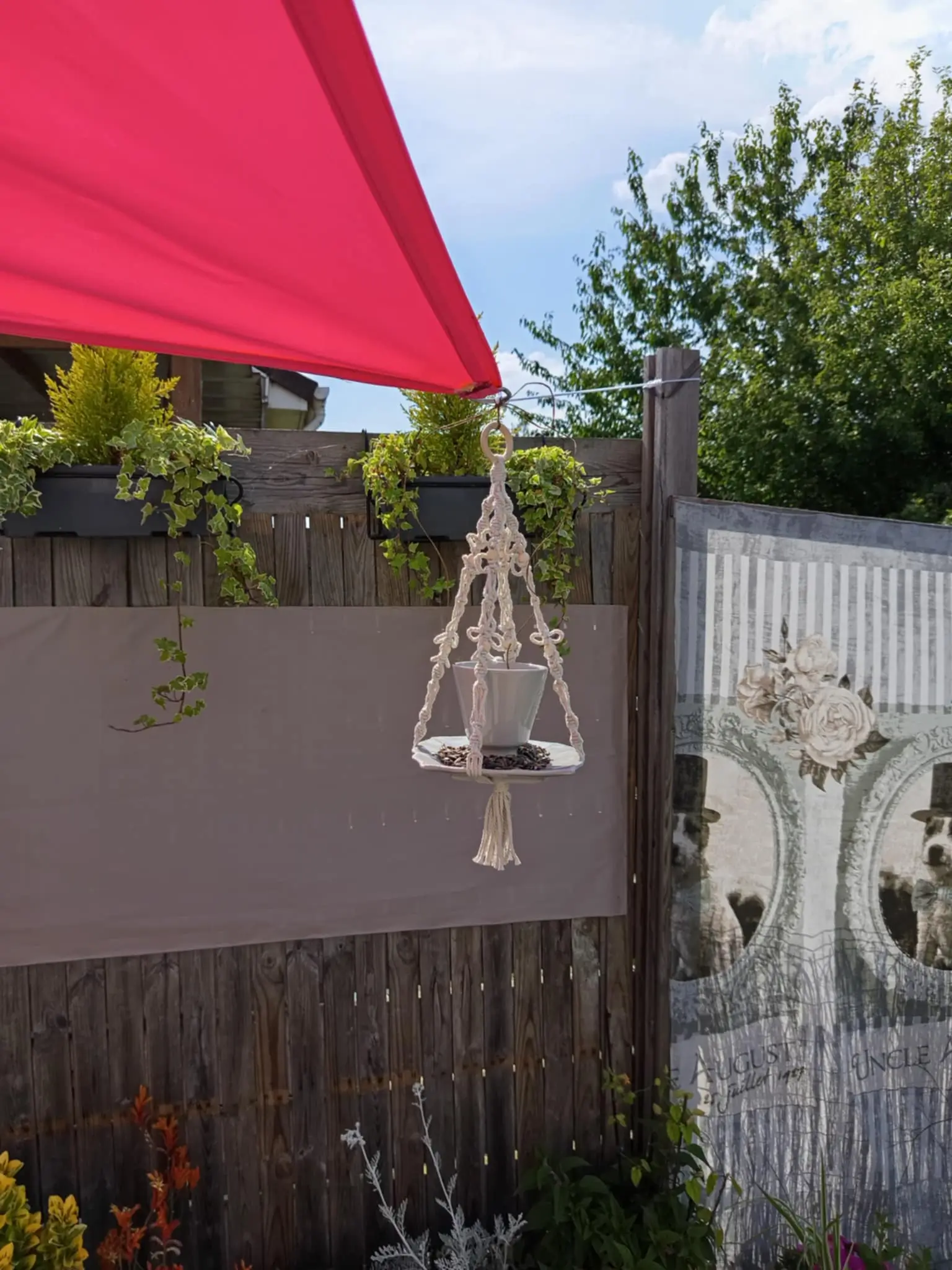 Mangeoire grise suspendue sur une toile d'ombre dans une terasse