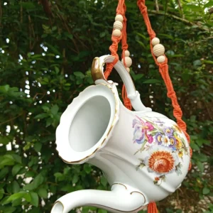 Une mangeoire fait avec une théière et un support en macramé fait main