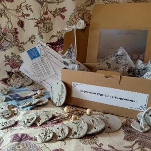 le kit DIY Impression Végétale - 2 suspensions - ouvert avec pièces d'ariles, perles, ciseaux, fiches technique, emballage, fils