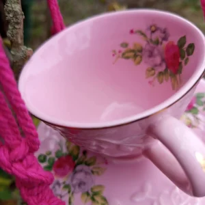 Mangeoire romantique rose avec des reliefs suspendue dans un arbre